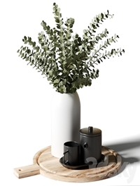 A bouquet of eucalyptus in a white vase, and a teapot with a cup on a wooden board